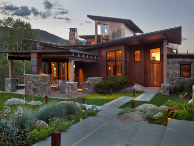 Modern home with stone and wood design, big windows, and landscaped yard with pathways and greenery