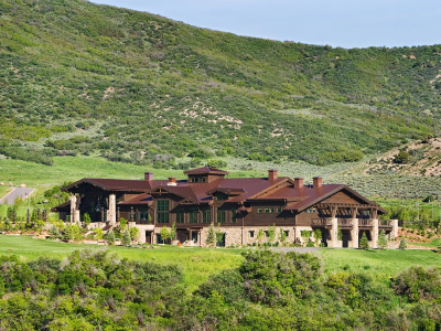 Large hospitality building with stone and wood design, set in a lush green mountainous landscape.